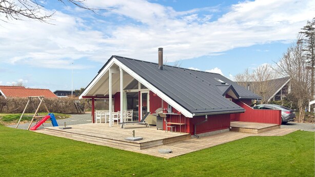 Une maison avec un toit en pente, une véranda et une petite terrasse.