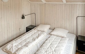 Ein Schlafzimmer mit Bett, Nachttisch, Lampe und Kleiderschrank.