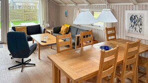 Une pièce chaleureuse avec une table à manger en bois, des chaises, un canapé et une fenêtre avec des rideaux.
