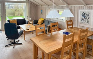 Ein gemütliches Zimmer mit einem Holztisch, Stühlen, einer Couch und einem Fenster mit Vorhängen.