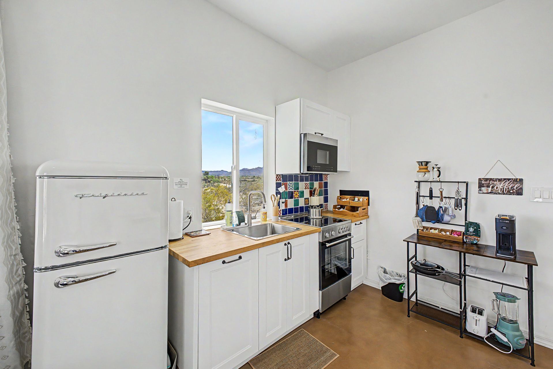 A compact kitchen with a refrigerator, stove, microwave, and a coffee station.