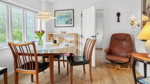A dining area with a table, chairs, a vase of flowers, and a painting on the wall.