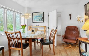 Ein Essbereich mit Tisch, Stühlen, einer Blumenvase und einem Gemälde an der Wand.