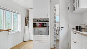 A kitchen with white cabinets, a built-in oven, and a window with a view of trees.