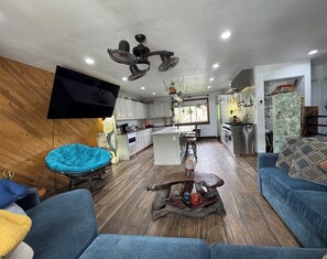 Una sala moderna con un sofá azul, una mesa de centro de madera y un televisor montado en la pared.