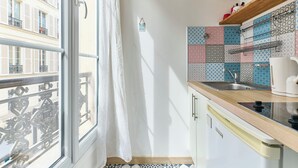 A compact kitchen with a window, patterned tiles, a sink, and a microwave. - Opera · 9th · Cosy Studio with Mezzanine – managed by Mey Agency (Paris)