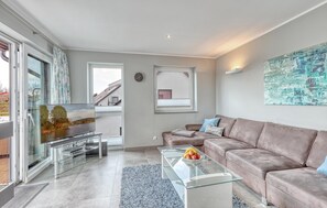 Ein modernes Wohnzimmer mit einem Glastisch, einer Ledersofa und einem Fernseher auf einem Glasfuß.