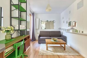 Una sala moderna con un sofá, una mesa de centro, un escritorio con una silla y una estantería.