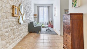 Una sala de estar con una pared de piedra, un sofá, un aparador de madera y una ventana con cortinas.