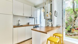 Una cocina moderna con armarios blancos, encimera de madera, horno empotrado y lámparas colgantes.
