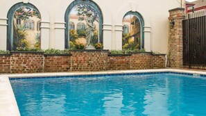 Une piscine avec un mur en briques et trois fenêtres en arc.