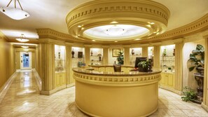 Un hall d’hôtel luxueux, doté d’un grand comptoir d’accueil, d’élégantes colonnes et d’un lustre.