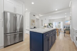 Una cocina moderna con electrodomésticos de acero inoxidable, encimera de mármol y una isla azul.