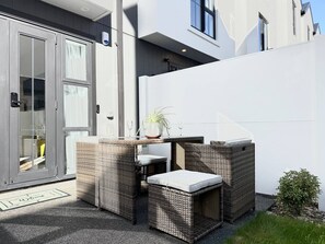 Ein moderner Sitzbereich im Freien mit Rattanmöbeln und einem kleinen Tisch.
