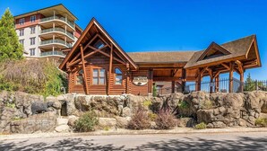 Un bâtiment de style cabane en rondins, doté d’un mur de soutènement en pierre, d’un balcon et d’une enseigne indiquant « Big Bear ».