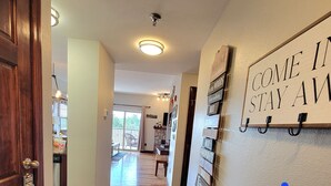 Un couloir avec une porte en bois, un tapis à motifs, une enseigne fixée au mur et une vue sur un coin repas.