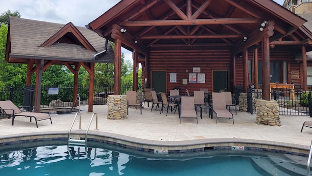 Un espace extérieur abrité comprenant une piscine, des chaises longues et un pavillon en bois.
