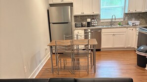 A modern kitchen with white cabinets, stainless steel appliances, and a dining area with a table and chairs. - Tranquil 1-bedroom apartment with AC in cozy Alvin (Alvin)
