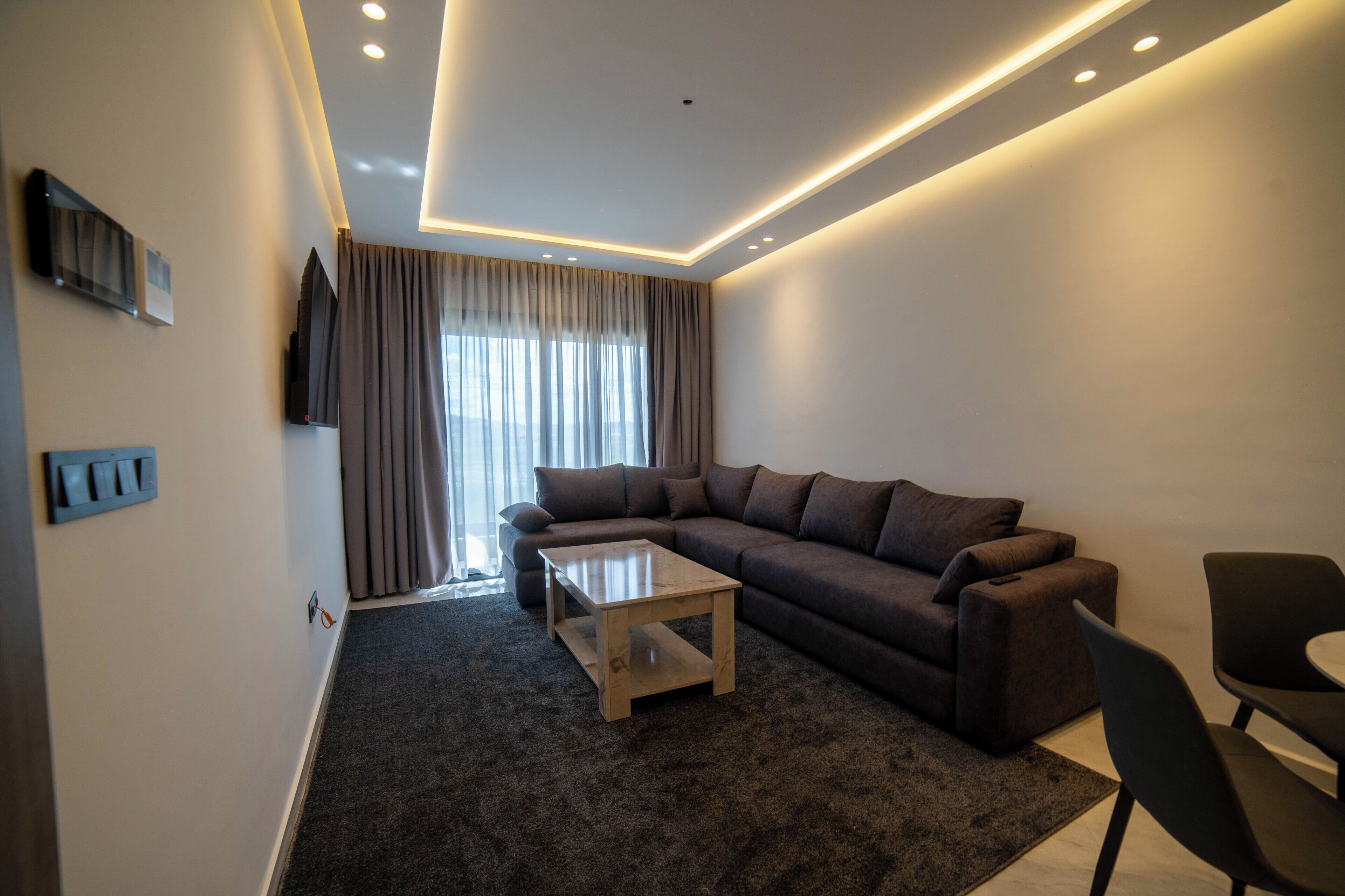 Una sala moderna con un sofá modular, una mesa de centro y un televisor montado en la pared.