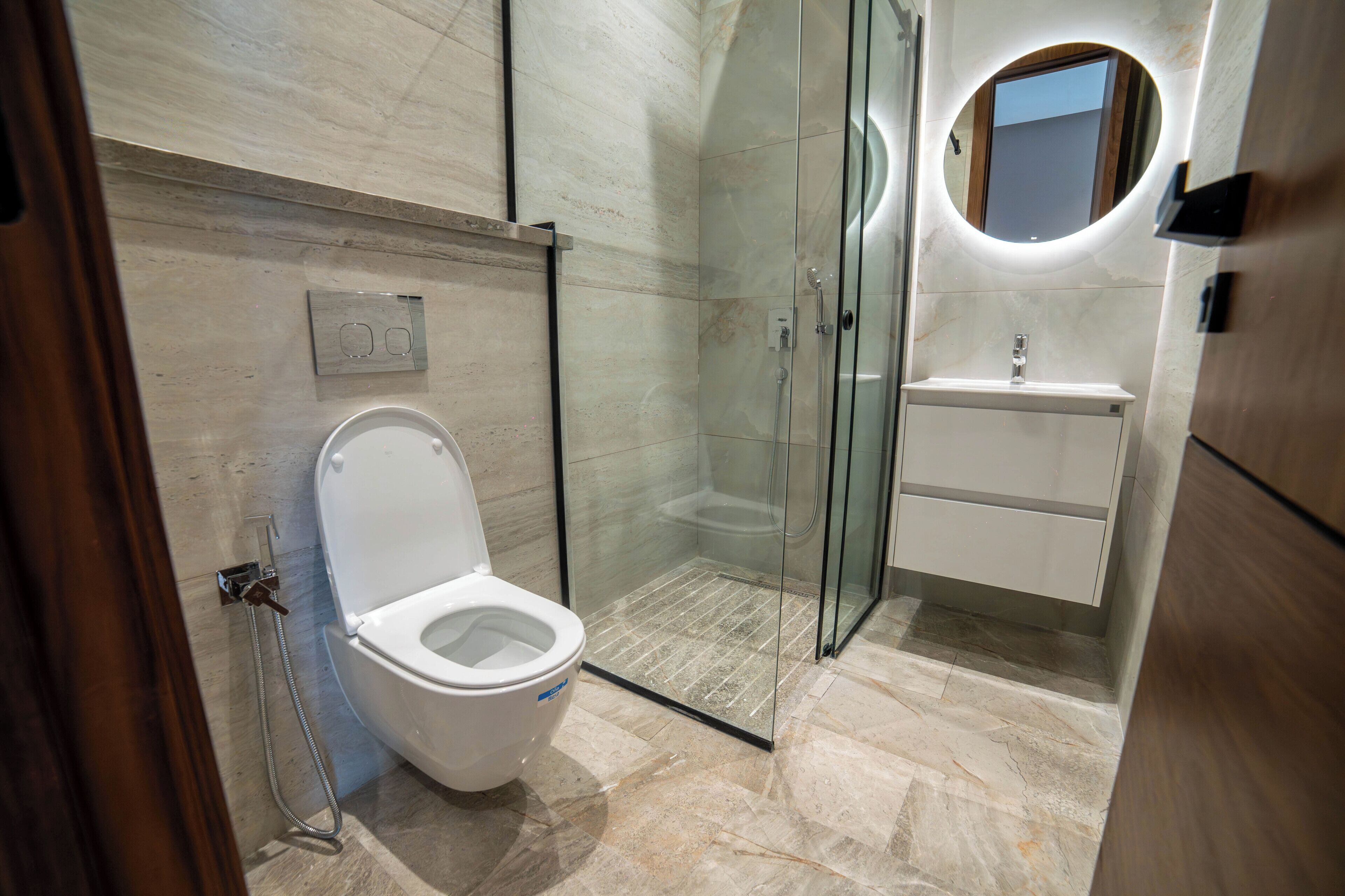 A modern bathroom with a glass-enclosed shower, a toilet, and a sink with a mirror.