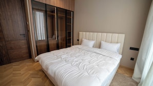 Un dormitorio con una cama grande, un armario de madera y un armario con puerta de vidrio corredera.