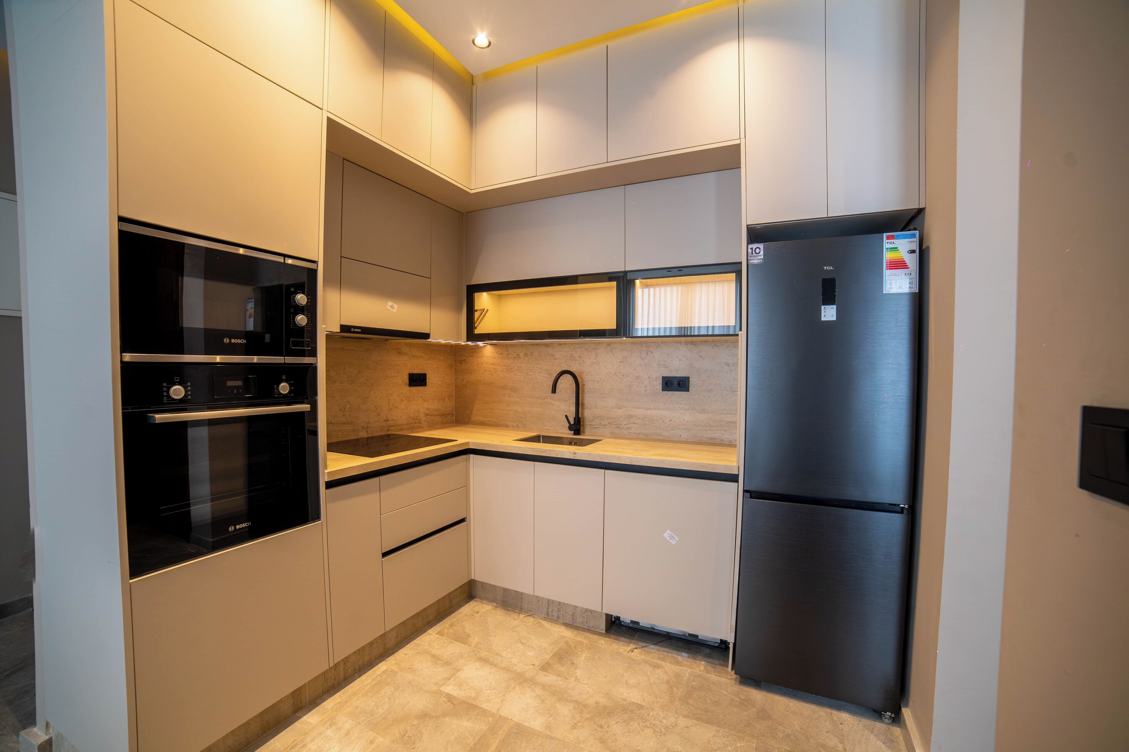 A modern kitchen with built-in appliances, a sink, and a refrigerator.