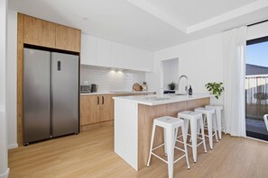 Eine moderne Küche mit einer zentralen Kochinsel, Barhocker und einem großen Kühlschrank.