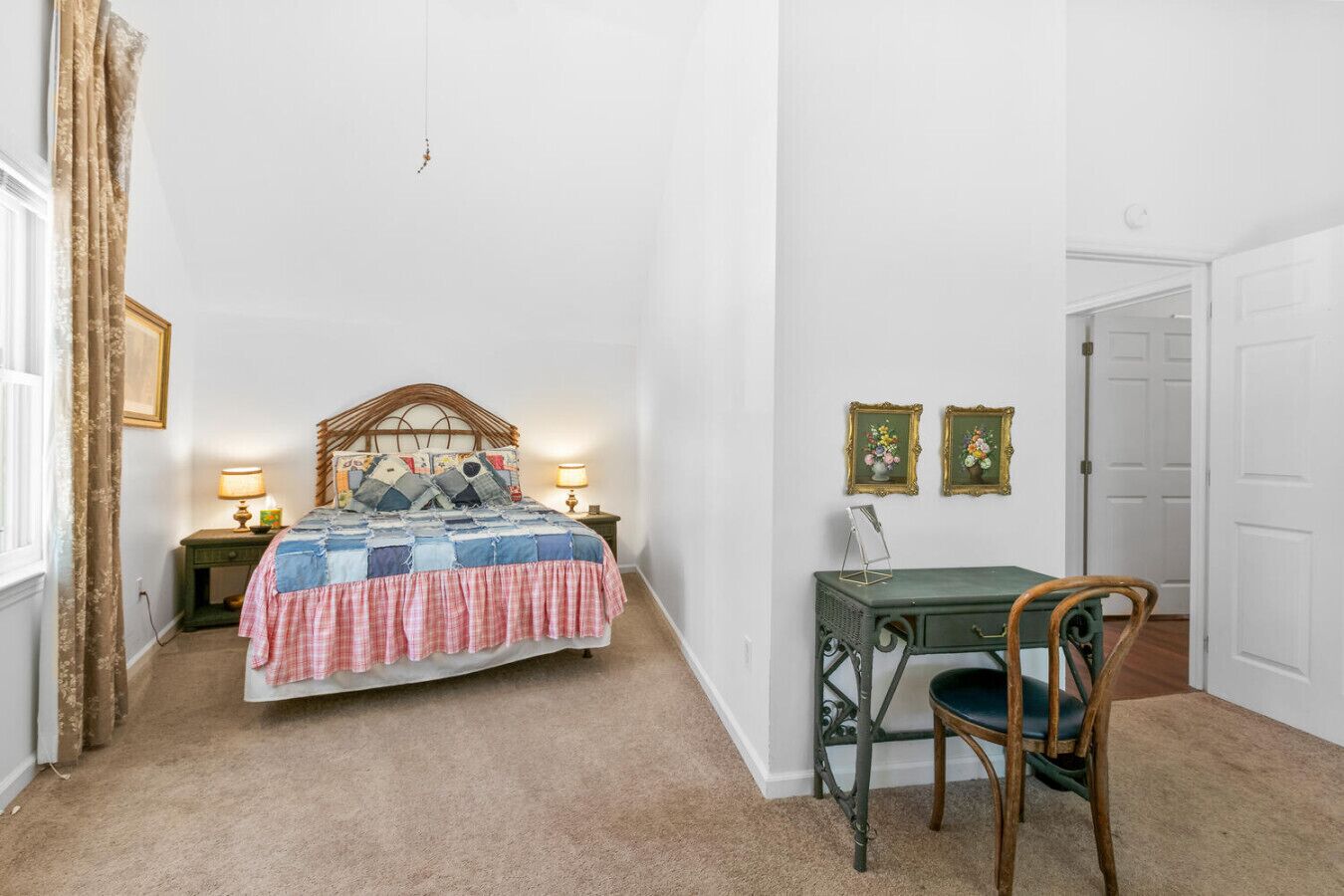 A bedroom with a bed, bedside tables, a desk, a chair, and two framed pictures on the wall.