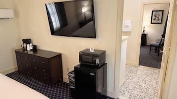 Habitación de hotel con televisión de pantalla plana, cómoda, microondas y cama.