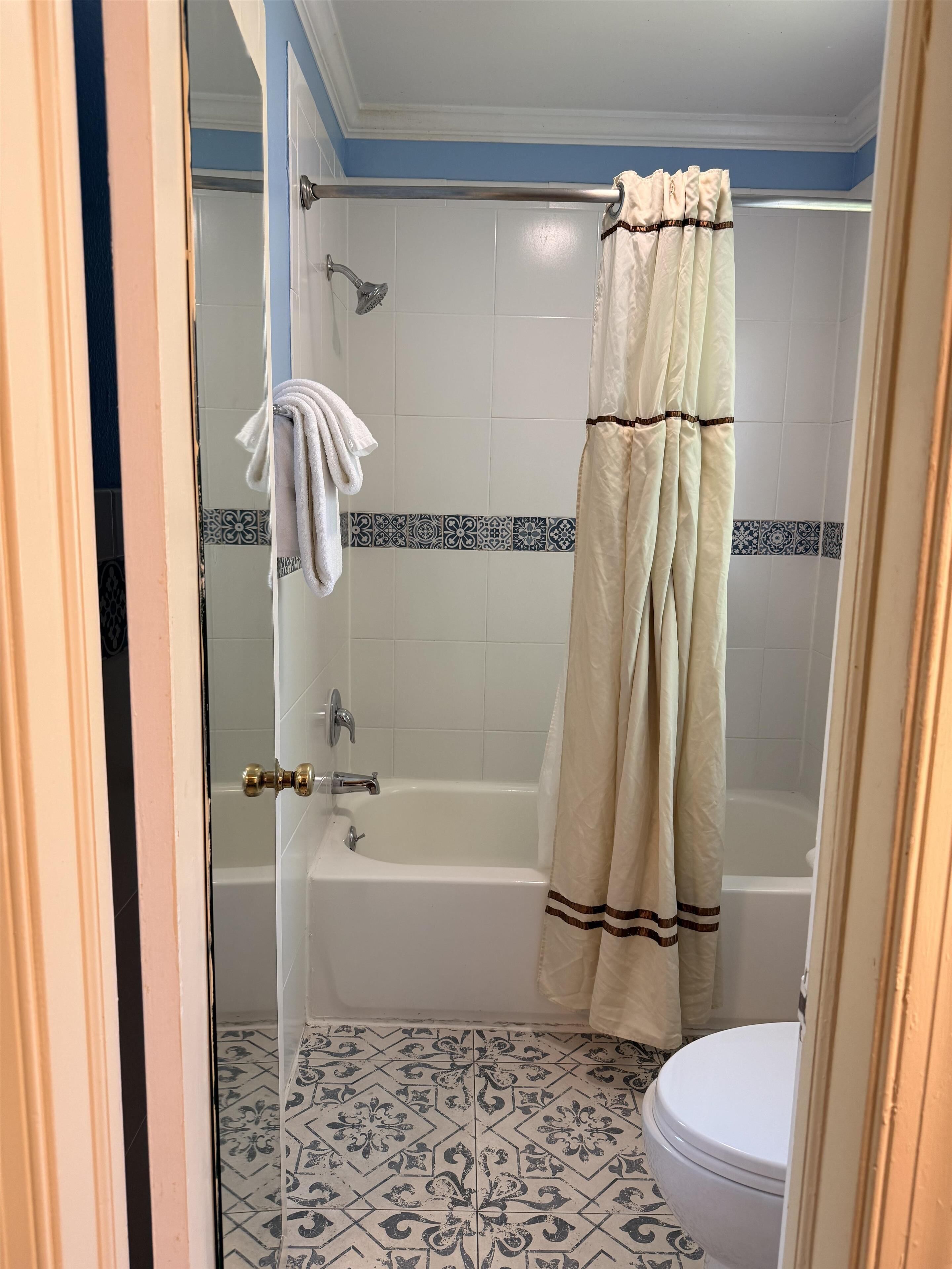 Un baño con bañera, cortina de ducha y retrete.