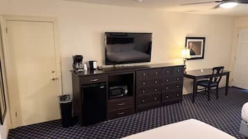 Ein Hotelzimmer mit einem Bett, einem Fernseher, einer Kaffeemaschine, einem Schreibtisch und einem Stuhl.