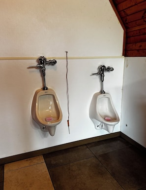 Two urinals mounted on a wall with a wooden ceiling. - The Knot & Pine Cabin - Minutes from Sturgis - Sleeps 8 (Sturgis)