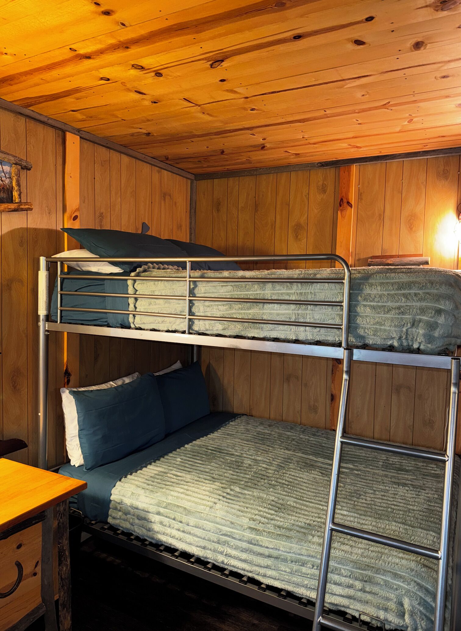 Habitación con literas, paredes de madera y una escalera de metal.