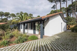 A modern house with a white exterior, a tiled roof, and a covered porch. - Charming house between Hossegor golf and Capbreton with patio under the pines (CAPBRETON)
