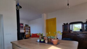 Ein Zimmer mit Holztisch, Topfpflanzen, einer gelben Tür und einem Schrank mit Gläsern.