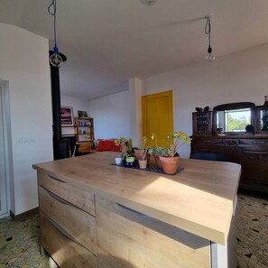 Ein Zimmer mit Holztisch, Topfpflanzen, einer gelben Tür und einem Schrank mit Gläsern.