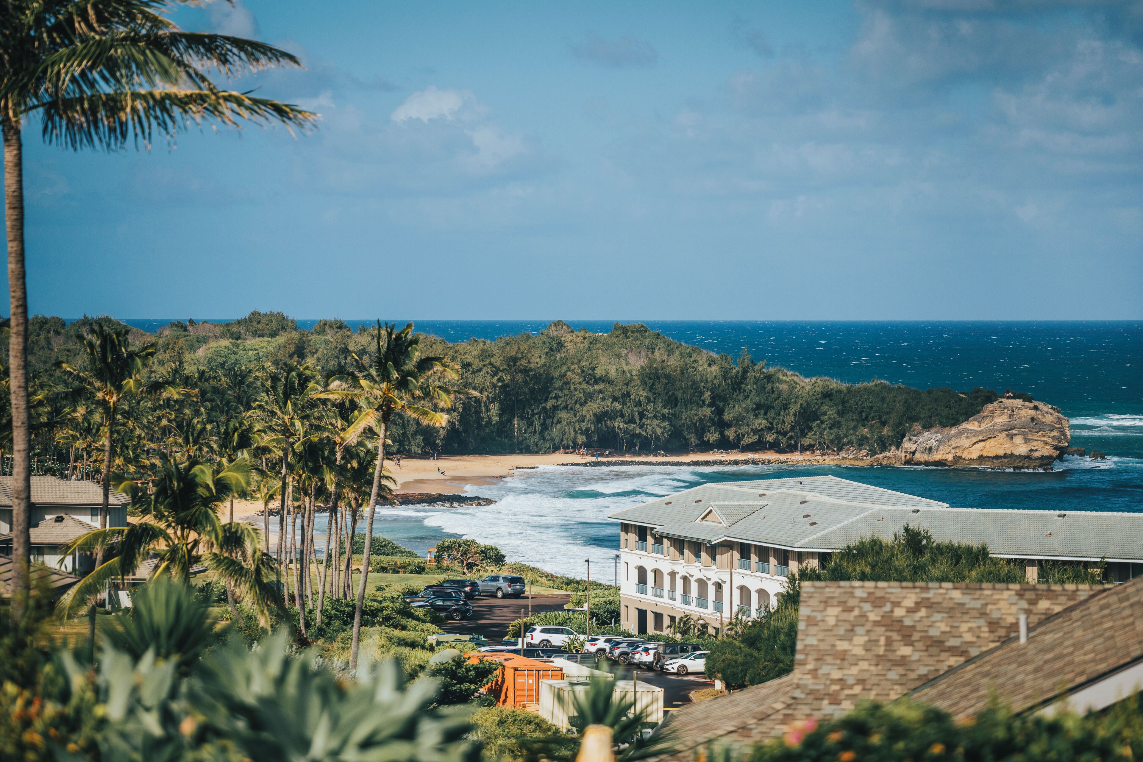 Un hotel frente al mar, con vistas al océano, una playa y un promontorio rocoso.