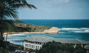 A coastal building with a view of the ocean and a rocky outcrop.