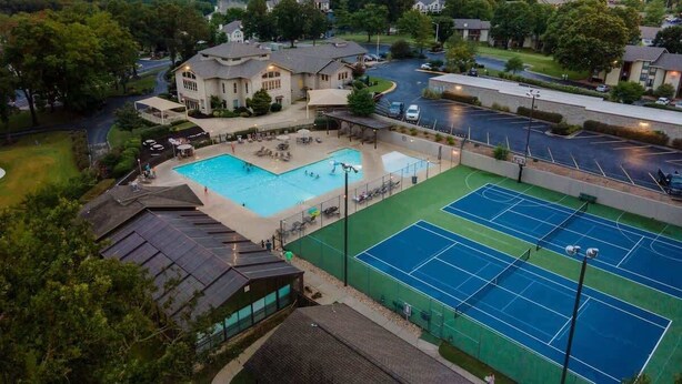 Een woonwijk met een zwembad, tennisbanen en huizen.