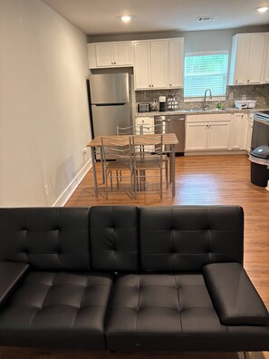 Una cocina moderna con gabinetes blancos, electrodomésticos de acero inoxidable y un comedor con mesa y sillas.