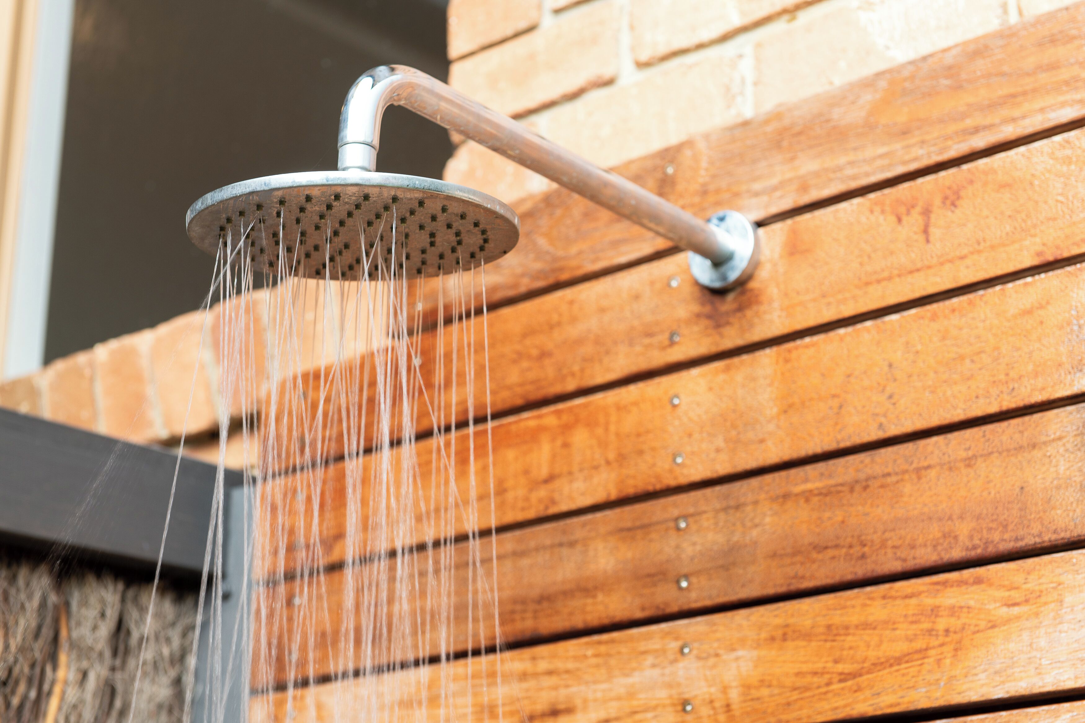 A showerhead with water flowing from it, mounted on a wooden surface.