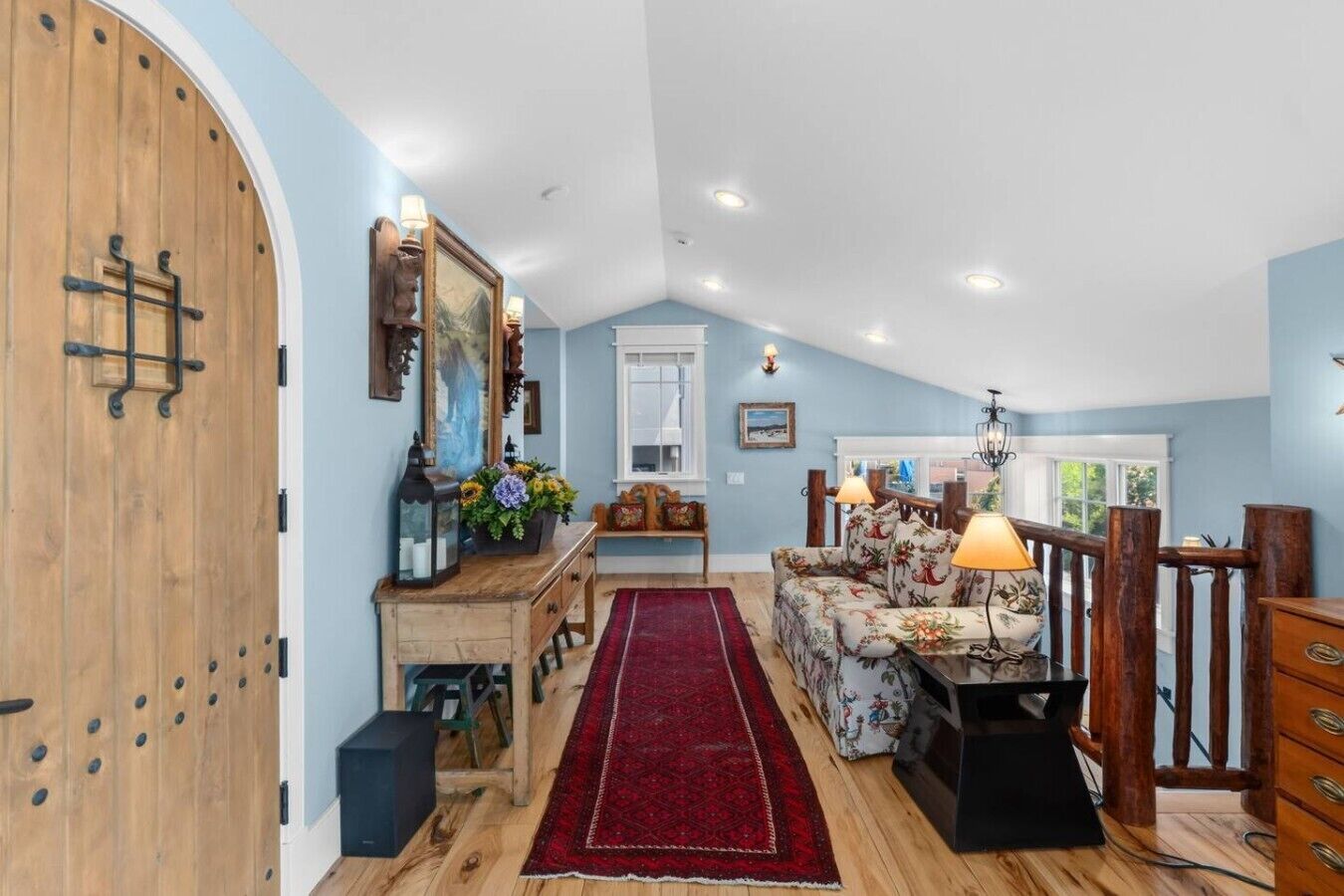 Una habitación con puerta de madera, alfombra roja, un sofá y una lámpara.