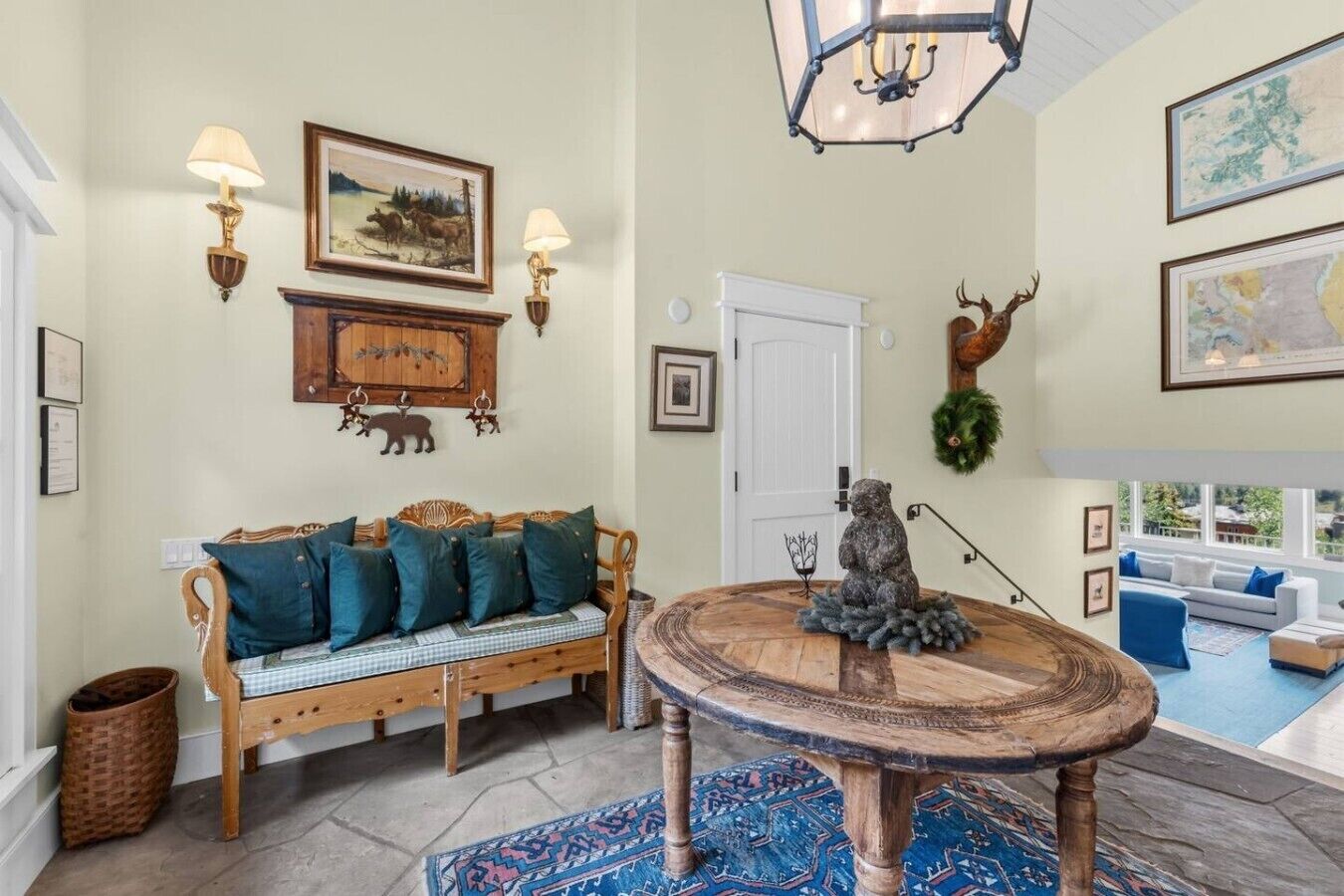 A cozy living room with a wooden sofa, a round coffee table, and a decorative deer head.