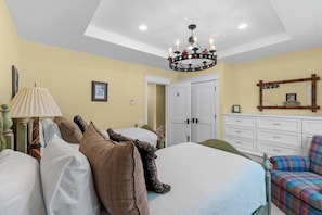 Un dormitorio con cama, una silla, un tocador, un espejo y una araña.