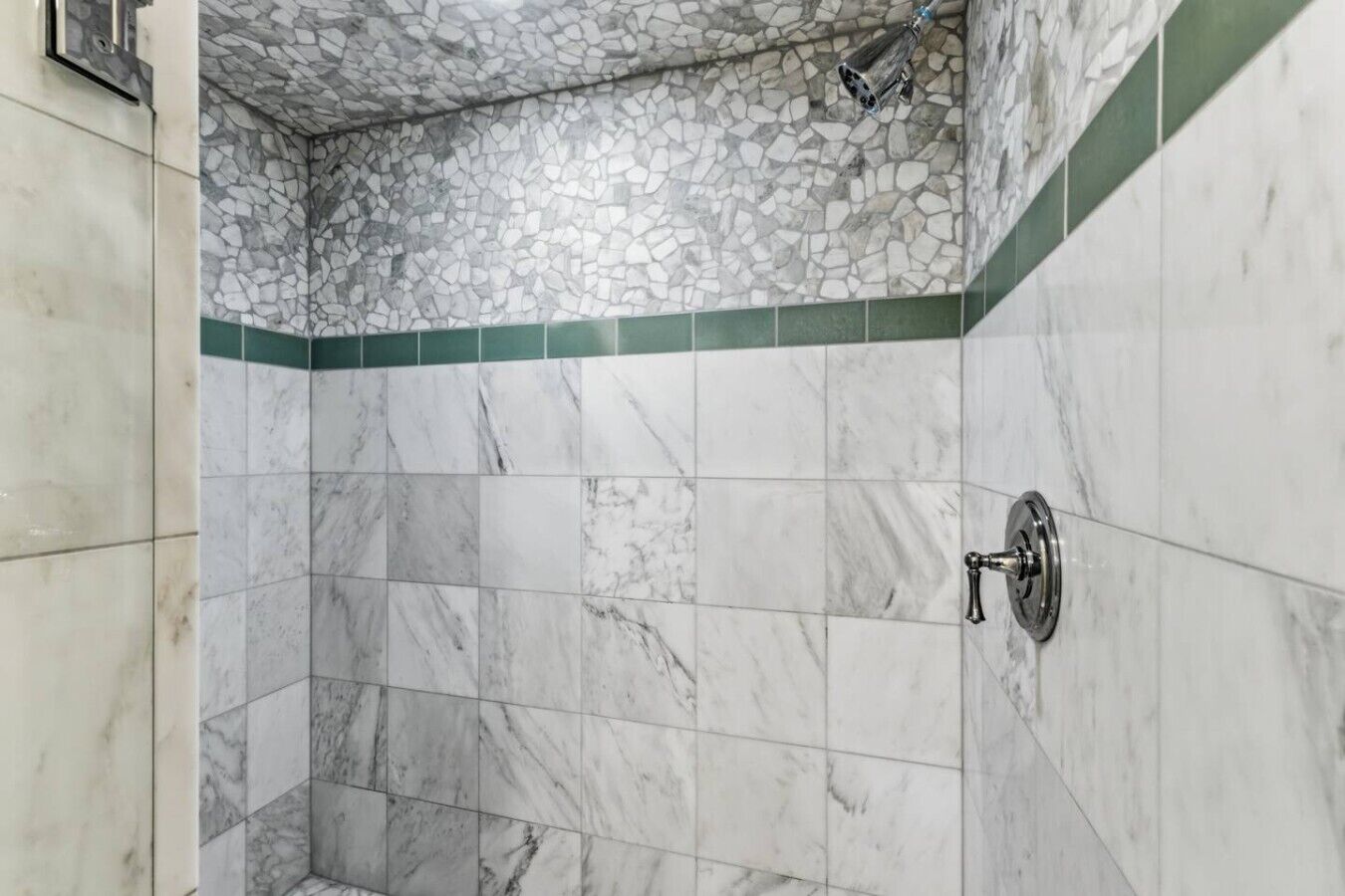 Une salle de bain avec un espace douche dotée d’un plafond en mosaïque de pierre et d’une pomme de douche fixée au mur.