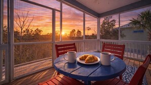 Een overdekt terras met een tafel en stoelen, met uitzicht op een schilderachtig zonsondergang.