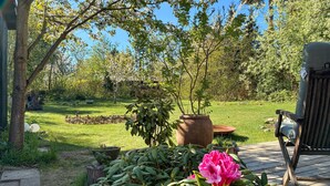 Ein Garten mit einer Holzterrasse, Kübelpflanzen und einem Stuhl.
