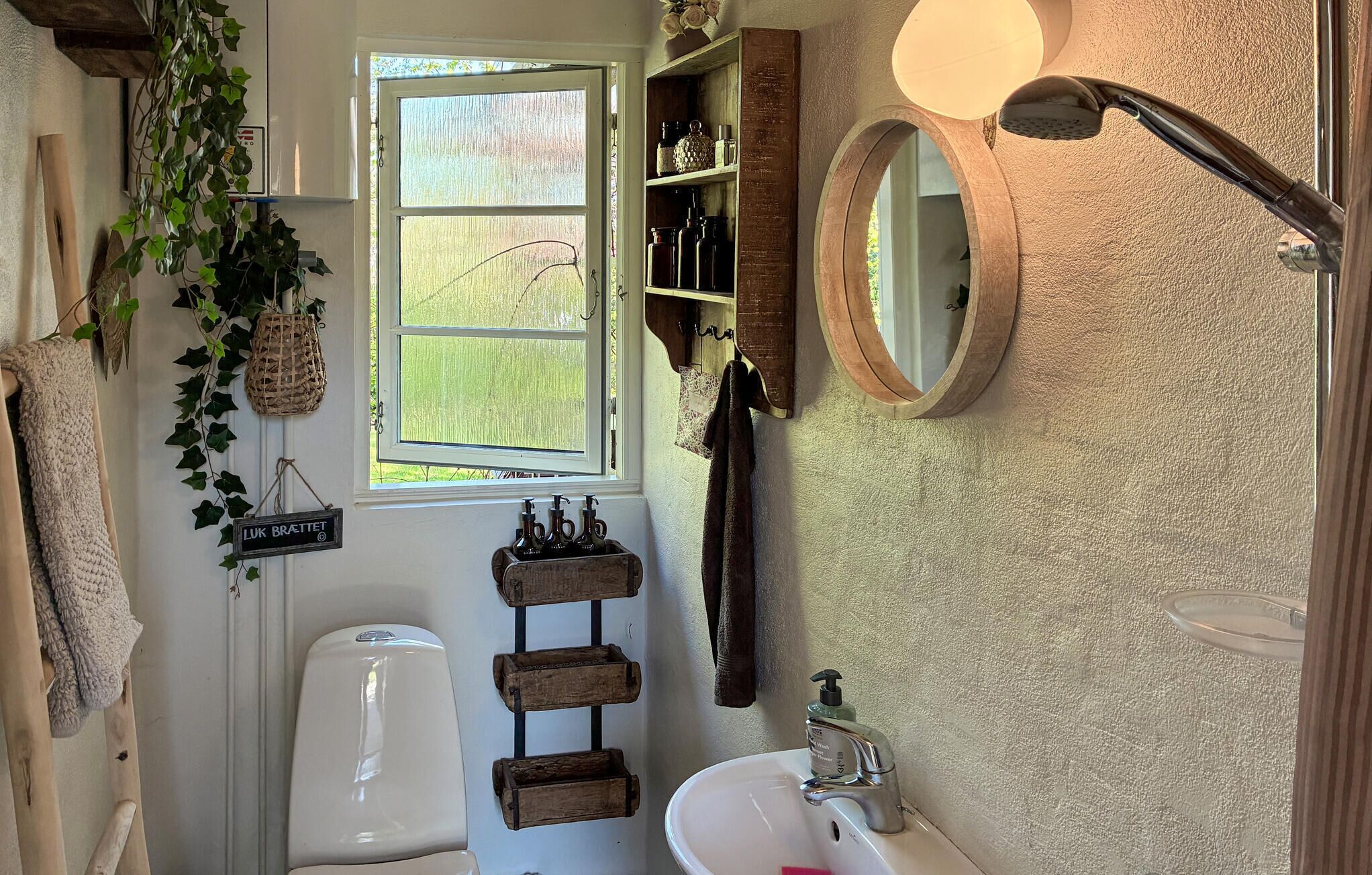 Een badkamer met toilet, wastafel, spiegel en raam.