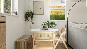 A modern kitchen with a dining table, chairs, a hanging light fixture, and a view of a field through the window. - Happy's Hideout, Downtown w/ Private Lawn (Ellensburg)