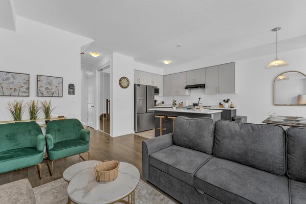 A modern living room with a grey sofa, a green sofa, and a white coffee table.